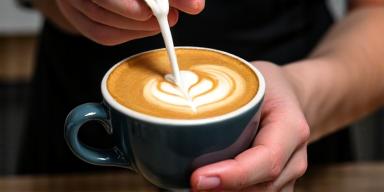Barista pouring latte art into a cup of coffee
